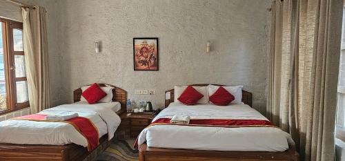 1 dormitorio con 2 camas y almohadas rojas en Jungle Safari Lodge - Chitwan National Park,Sauraha, en Sauraha