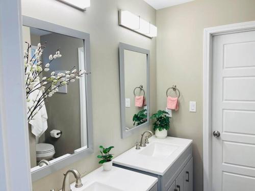 - une salle de bains blanche avec deux lavabos et un miroir dans l'établissement Spacious home, 3 king beds, huge backyard near UM, à Memphis