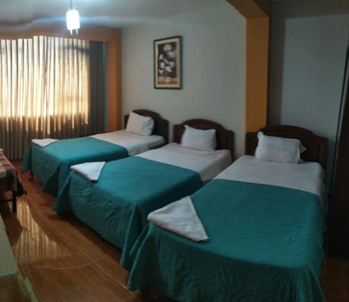 Habitación de hotel con 2 camas con sábanas verdes en Hospedaje Concordia en Chiclayo
