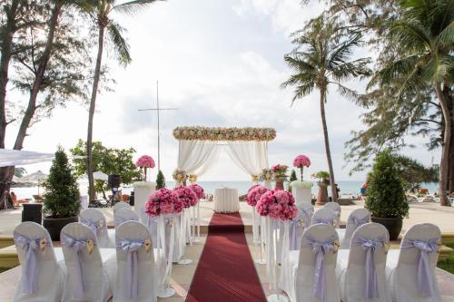 a wedding ceremony at the beach with white chairs and pink flowers at Beyond Kata in Kata Beach