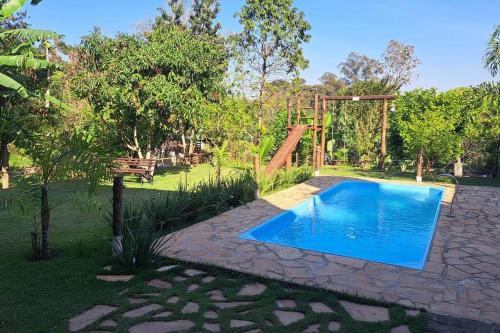 a swimming pool in a garden with a wooden structure at Casa de campo (chácara) em Louveira in Louveira