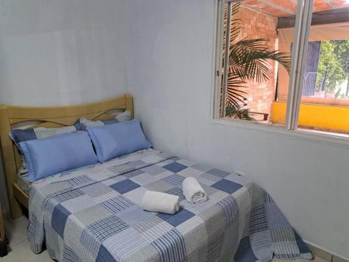 a bedroom with a bed with blue pillows and a window at Casa de campo (chácara) em Louveira in Louveira