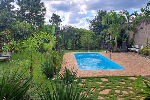 a swimming pool in a garden with a bench at Casa de campo (chácara) em Louveira in Louveira