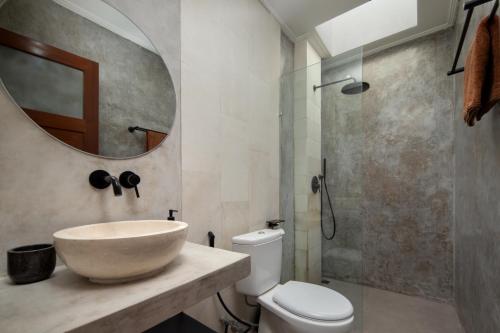 a bathroom with a sink and a toilet and a mirror at Villa Bella Rose Canggu in Canggu