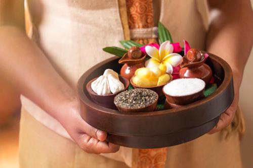 a woman holding a bowl of chocolates and desserts at Beyond Kata in Kata Beach