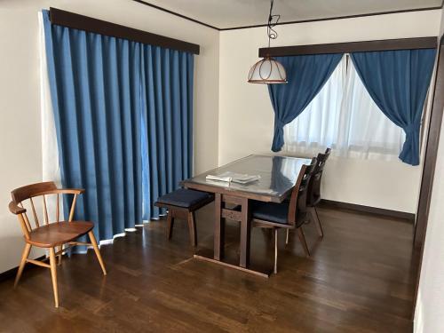 uma sala de jantar com cortinas azuis e uma mesa e cadeiras em Guest House Fuji no Yado Akebono Building A - Vacation STAY 74316v em Fujiyoshida