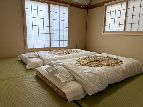 três camas num quarto com duas pizzas em Guest House Fuji no Yado Akebono Building A - Vacation STAY 74316v em Fujiyoshida