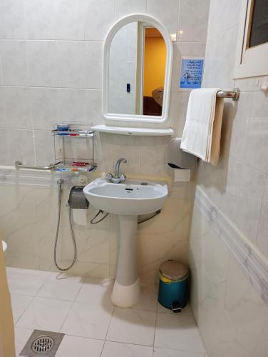 a white bathroom with a sink and a mirror at السرايا الاولى للشقق المخدومة in Al Hofuf