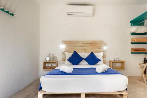ein Schlafzimmer mit einem großen Bett mit blauen Kissen in der Unterkunft Casa Toloc Tulum in Tulum