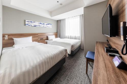 東京にあるファーイーストビレッジホテル東京有明のベッド2台、薄型テレビが備わるホテルルームです。