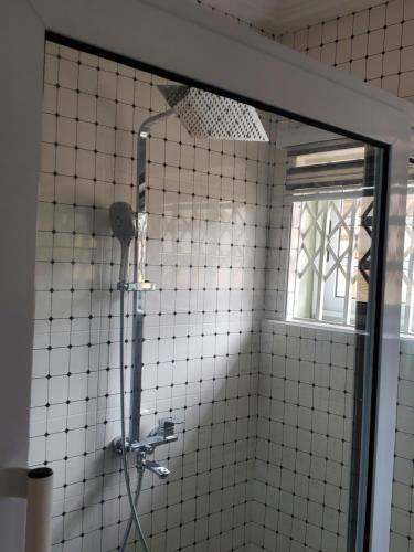 W wyłożonej białymi kafelkami łazience z oknem znajduje się prysznic. w obiekcie Casa Consuelo Guest House w mieście Sekondi-Takoradi