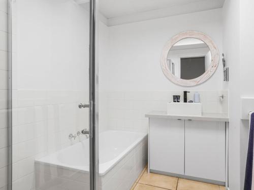 a white bathroom with a tub and a sink and a mirror at Quarterdeck in Portsea