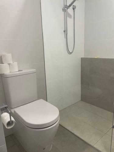 a white bathroom with a toilet and a shower at Pandanus Paradise. Newly renovated 4 bedroom home in Cabarita Beach