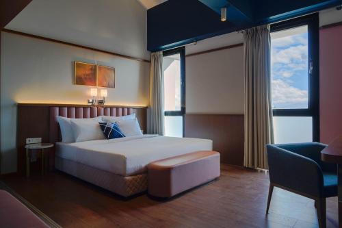 a hotel room with a bed and a chair and window at Four Points Express by Sheraton Bursa Nilufer in Bursa