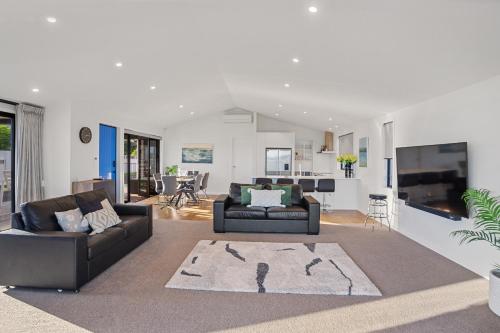 a living room with two couches and a tv at Waterfront Oasis - Omokoroa Holiday Home in Omokoroa