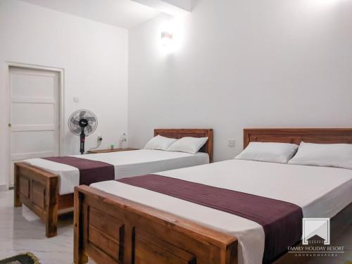 阿努拉德普勒的住宿－Family Holiday Resort，白色客房的两张床,配有2张床