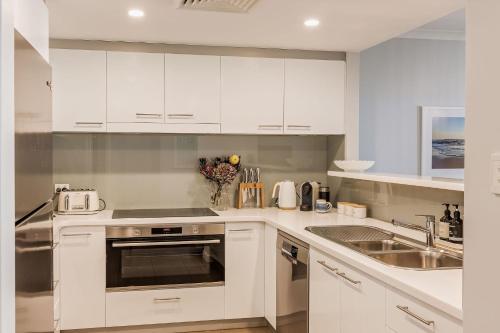 a kitchen with white cabinets and a sink at 10 Steps in Yallingup