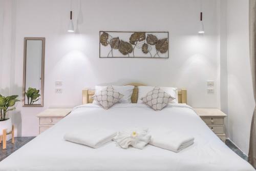 a white bedroom with a large white bed with towels on it at Apple Villas in Haad Chao Phao