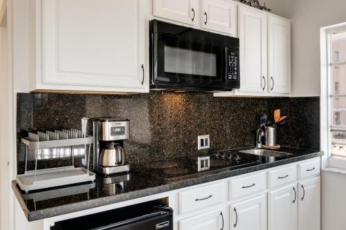 a kitchen with white cabinets and a black counter top at Best Location SOBE Top Floor 2 min to beach & fun in Miami Beach
