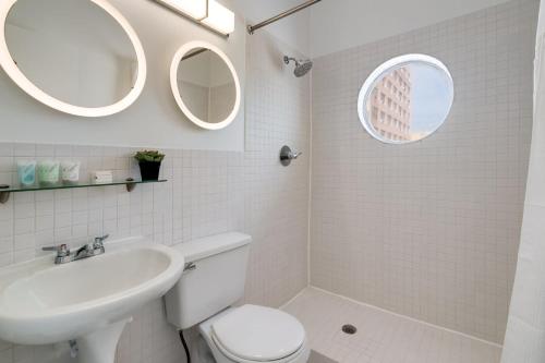 a bathroom with a toilet sink and two mirrors at Best Location SOBE Top Floor 2 min to beach & fun in Miami Beach