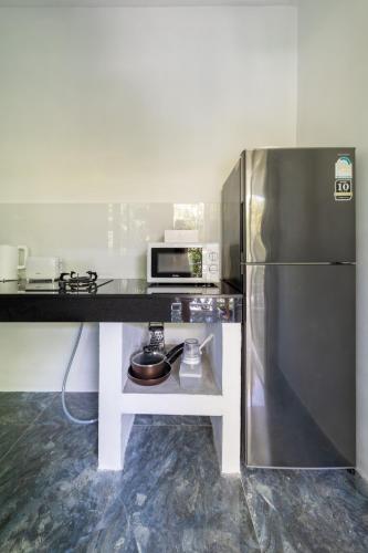 a kitchen with a stove and a refrigerator at Apple Villas in Haad Chao Phao