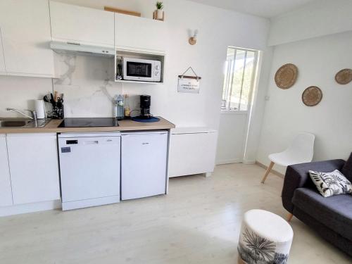 Il comprend une cuisine et un salon avec des placards blancs et un canapé. dans l'établissement Charmant appartement 4 couchages à 500m de la mer, parking inclus - Courseulles-sur-Mer - FR-1-746-15, à Courseulles-sur-Mer