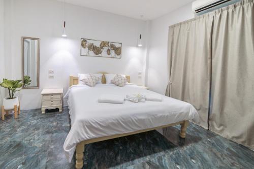 um quarto com uma grande cama branca e uma janela em Apple Villas em Haad Chao Phao