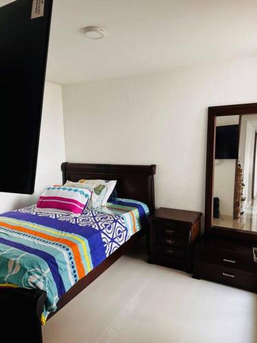 a bedroom with a bed and a dresser and a mirror at Cali Valle del Lili Apartamento in Cali