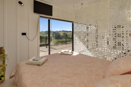 a bedroom with a bed and a large window at Valley View - Whangarei Tiny Home in Whangarei