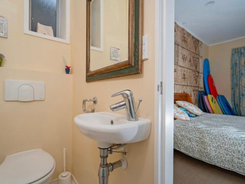 Un baño con lavabo, inodoro y una cama. en Kiwi Charmer - Onemana Holiday Home, en Opoutere