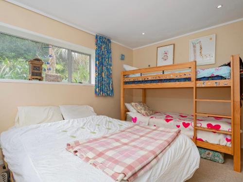 Un dormitorio con dos literas y una ventana. en Kiwi Charmer - Onemana Holiday Home, en Opoutere