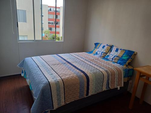 Un dormitorio con una cama con almohadas azules y una ventana en Habitación acogedora Orué, en Lima