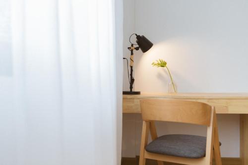 a desk with a lamp and a chair next to a curtain at Karpenter Lampang in Lampang