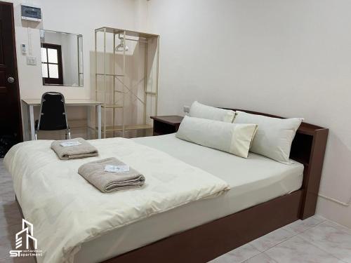 a bedroom with a bed with two towels on it at เอส ที อพาร์ทโฮเทล / S.T.ApartHotel in Ban Khao Rup Chang