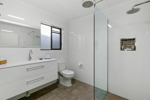 La salle de bains blanche est pourvue de toilettes et d'une douche en verre. dans l'établissement Comfort Inn on Main Hervey Bay, à Hervey Bay