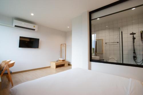 a bedroom with a large white bed and a shower at Karpenter Lampang in Lampang