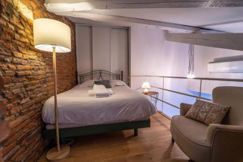 une chambre avec un lit et un mur de briques dans l'établissement Pargaminières by Yumē, à Toulouse
