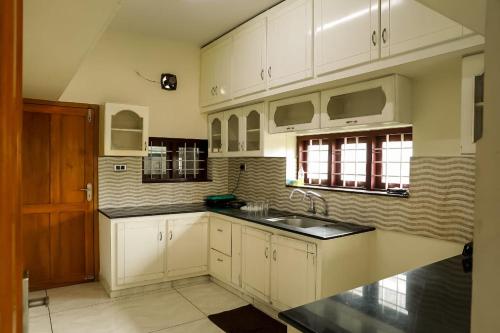 una cucina con armadi bianchi e lavandino di SILVER HOMES Service Apartments ad Alwaye