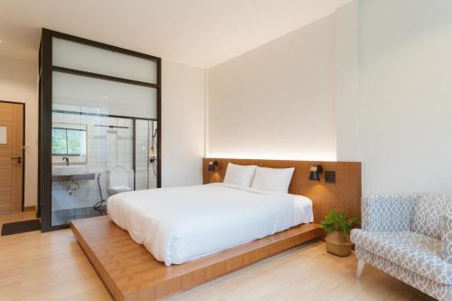 a bedroom with a large white bed and a chair at Karpenter Lampang in Lampang