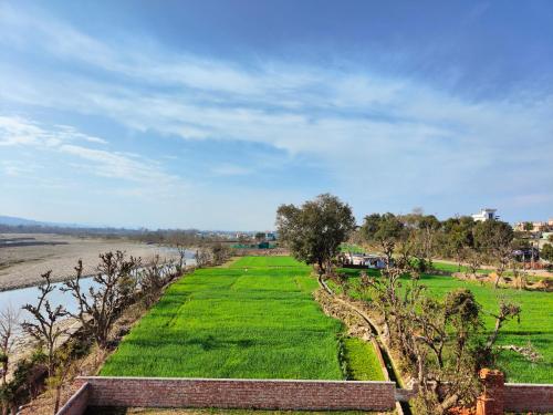 Rishikesh Shiv Dham Homestay في ريشيكيش: ميدان عشب أخضر بجانب نهر
