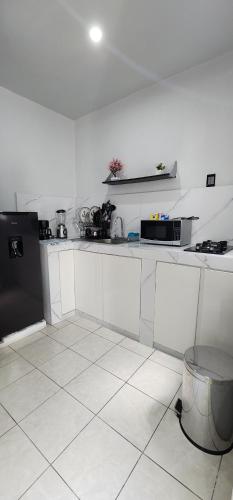 a kitchen with white cabinets and a black refrigerator at Departamento por plaza terraza oblatos in Guadalajara