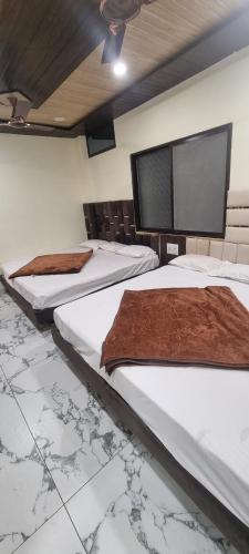 twee bedden in een kamer met een flatscreen-tv bij Hotel StarLight By i line in Ujjain