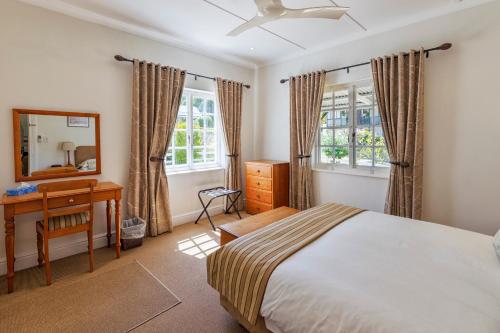 a bedroom with a bed and a dresser and a mirror at Belvidere Manor Lagoonside Cottages in Knysna