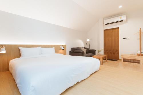 a bedroom with a large white bed and a chair at Karpenter Lampang in Lampang