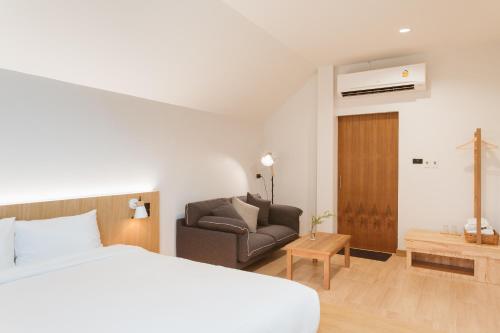 a bedroom with a bed and a couch in a room at Karpenter Lampang in Lampang