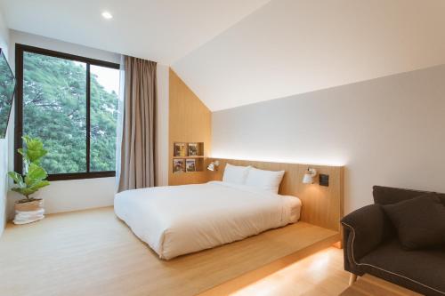a bedroom with a white bed and a couch at Karpenter Lampang in Lampang
