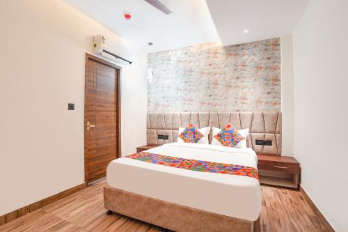 a bedroom with a large bed and a brick wall at FabHotel The Comfort Inn in Kānpur