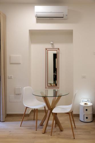 ein Esszimmer mit einem Glastisch und weißen Stühlen in der Unterkunft Sorelle Costa apartments in Caserta