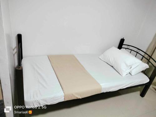 a bed with a black frame and white sheets and pillows at 3K’s Transient house in Bagac in Malawin