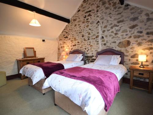 een slaapkamer met 2 bedden en een stenen muur bij 2 bed property in Instow INFOB in Westleigh